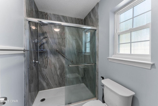 bathroom with a marble finish shower, a textured ceiling, and toilet