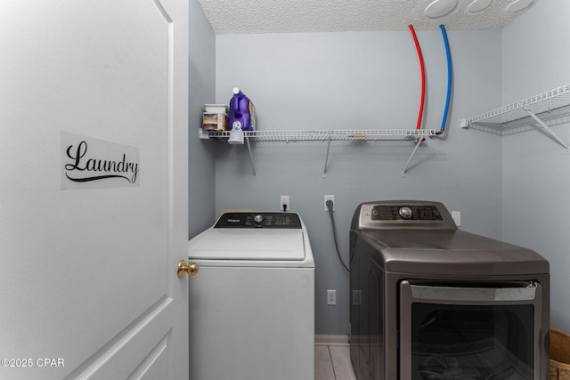 laundry area featuring a textured ceiling, laundry area, and washer and clothes dryer