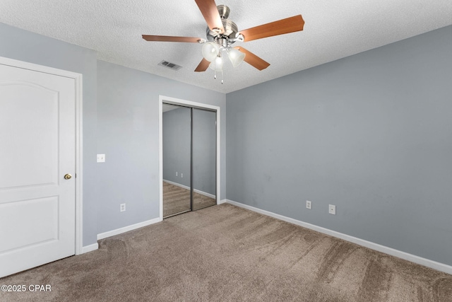 unfurnished bedroom featuring visible vents, a textured ceiling, a closet, carpet flooring, and baseboards