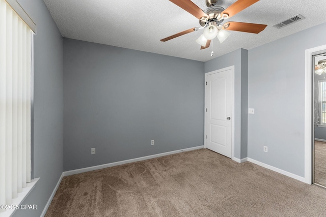 unfurnished bedroom with visible vents, carpet flooring, a textured ceiling, and baseboards