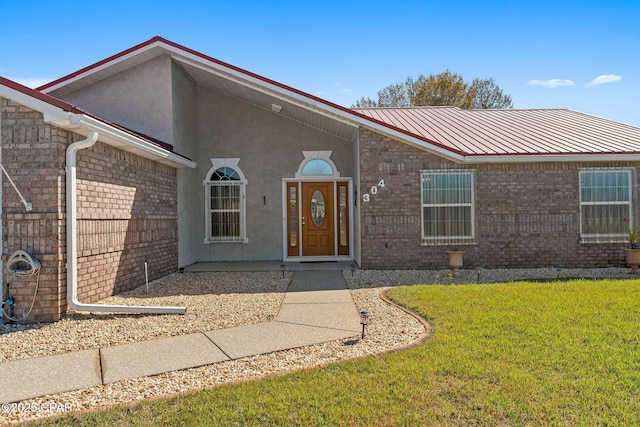 view of front of property featuring brick siding, metal roof, and a front yard