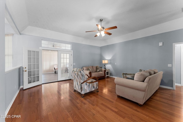 living room with a ceiling fan, hardwood / wood-style flooring, a tray ceiling, french doors, and baseboards