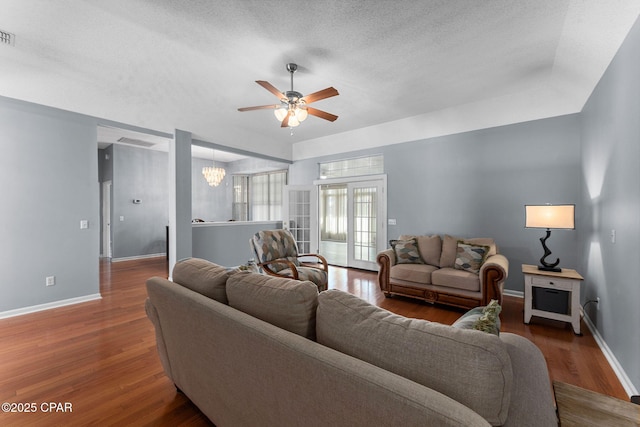 living room with visible vents, ceiling fan with notable chandelier, a textured ceiling, wood finished floors, and baseboards