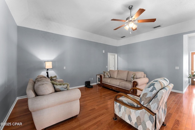 living area featuring visible vents, baseboards, ceiling fan, and wood finished floors