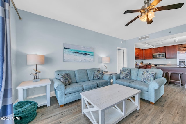 living area featuring baseboards, visible vents, light wood-style flooring, and ceiling fan