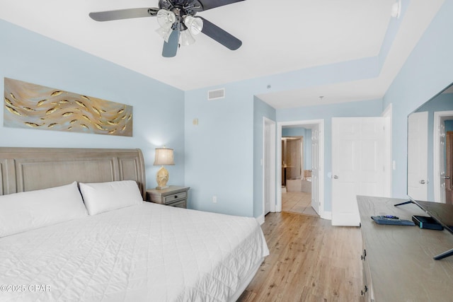 bedroom featuring visible vents, baseboards, ceiling fan, light wood-style flooring, and ensuite bathroom