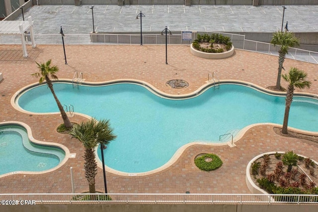 community pool with a patio area and fence