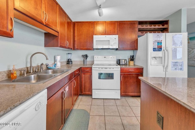 kitchen featuring a sink, white appliances, light tile patterned flooring, brown cabinetry, and rail lighting