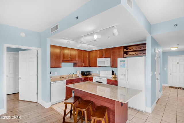 kitchen featuring a sink, visible vents, white appliances, and a breakfast bar area