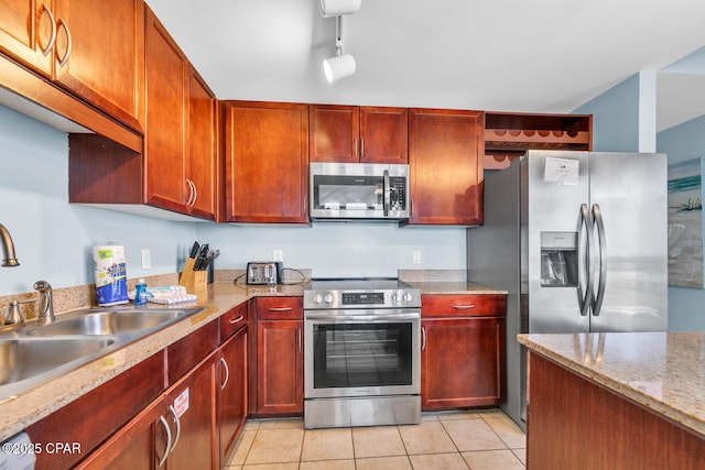 kitchen featuring light tile patterned flooring, a sink, reddish brown cabinets, and appliances with stainless steel finishes