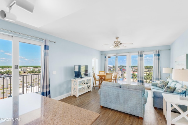 living room with wood finished floors, baseboards, and ceiling fan