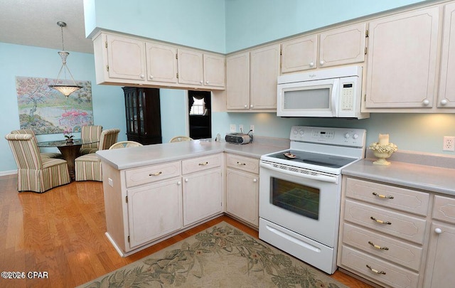 kitchen featuring light countertops, light wood-style flooring, a peninsula, hanging light fixtures, and white appliances