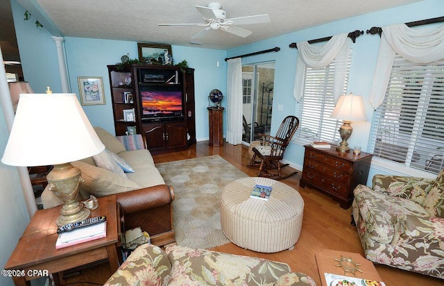 living area with a textured ceiling, a ceiling fan, and wood finished floors