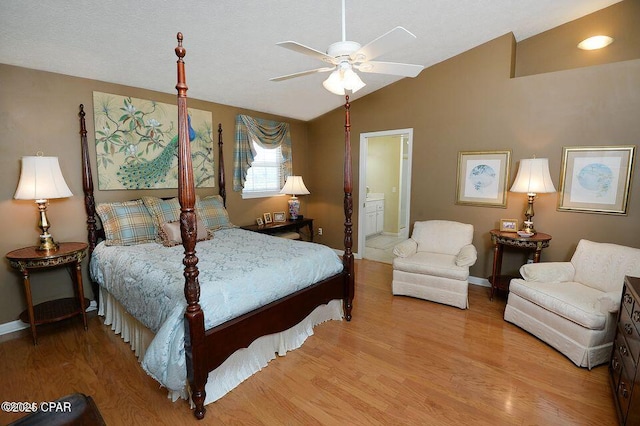 bedroom featuring ensuite bathroom, baseboards, light wood-style floors, and lofted ceiling