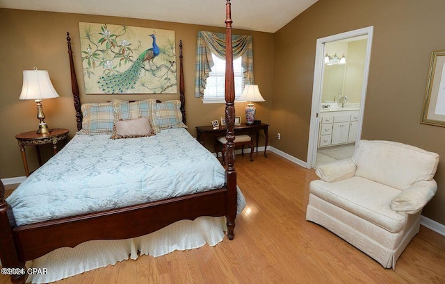 bedroom with ensuite bath, baseboards, lofted ceiling, and wood finished floors