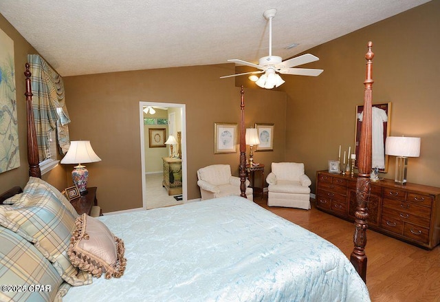 bedroom with vaulted ceiling, wood finished floors, and a textured ceiling