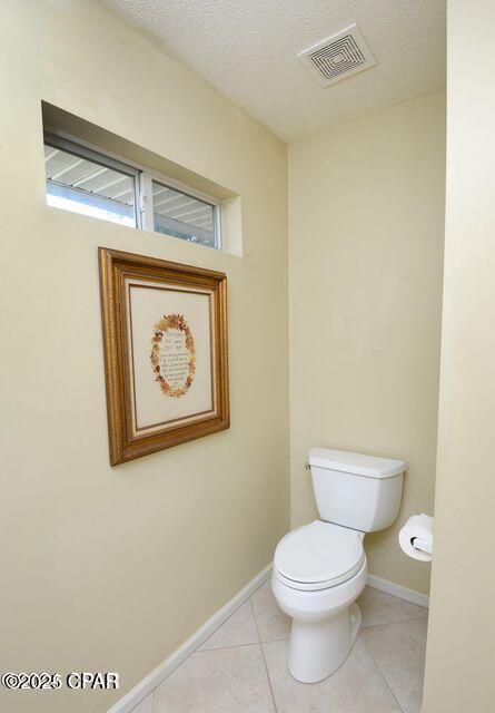 bathroom featuring visible vents, toilet, a textured ceiling, tile patterned flooring, and baseboards