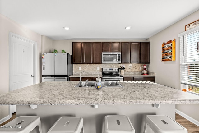 kitchen featuring a sink, dark brown cabinets, backsplash, and stainless steel appliances