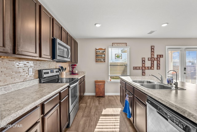 kitchen with tasteful backsplash, visible vents, light wood finished floors, appliances with stainless steel finishes, and a sink