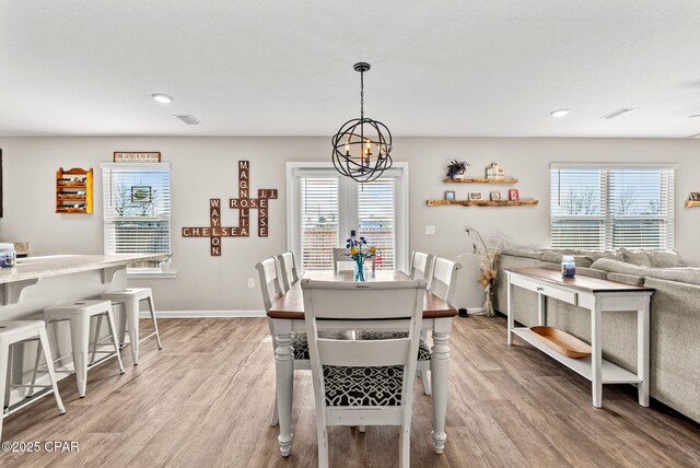 dining space with an inviting chandelier, a healthy amount of sunlight, and light wood-type flooring