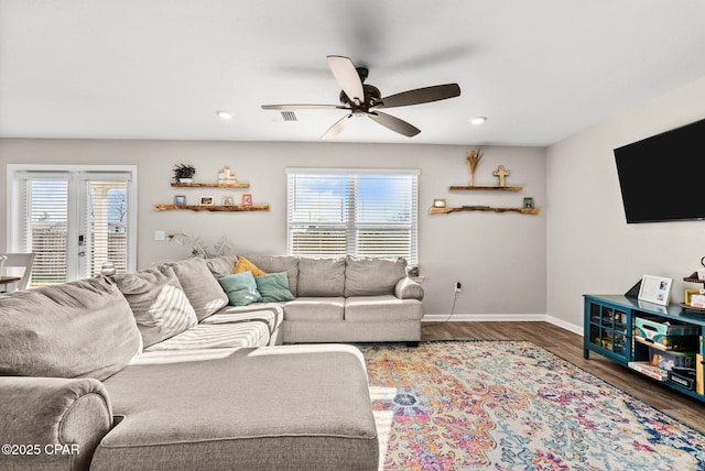 living area with visible vents, wood finished floors, baseboards, and ceiling fan