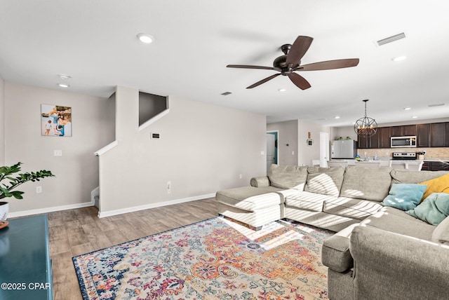 living area with recessed lighting, ceiling fan with notable chandelier, and light wood finished floors