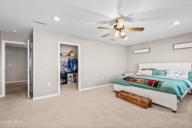 carpeted bedroom with a spacious closet, baseboards, visible vents, and ceiling fan