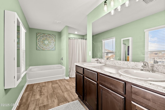 full bathroom featuring visible vents, wood finished floors, a garden tub, and a sink