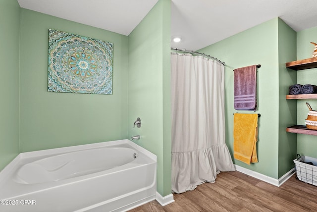 bathroom featuring a shower with curtain, baseboards, a garden tub, and wood finished floors