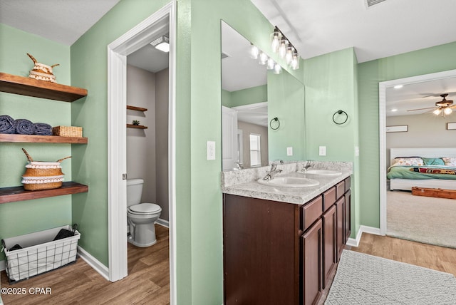 full bathroom featuring baseboards, double vanity, ensuite bathroom, wood finished floors, and a sink