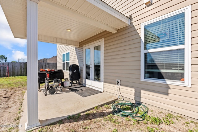 view of patio with area for grilling, french doors, and fence