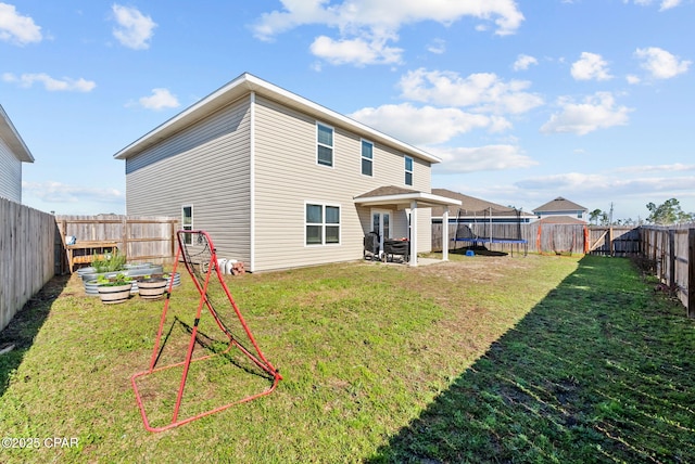 rear view of house featuring a garden, a trampoline, a lawn, and a fenced backyard