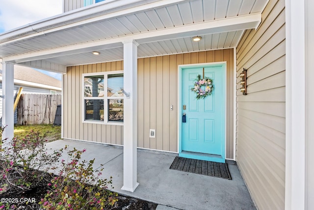 doorway to property with a porch, fence, and board and batten siding