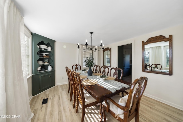 dining room featuring visible vents, baseboards, light wood-style floors, and an inviting chandelier