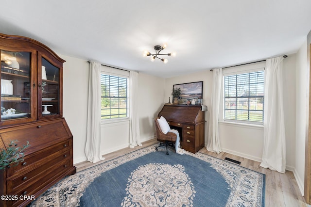 living area featuring a notable chandelier, plenty of natural light, visible vents, and light wood-style floors