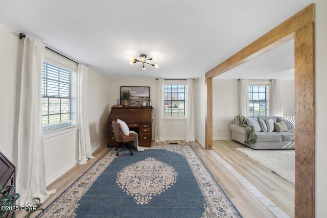 living area with baseboards, plenty of natural light, and wood finished floors