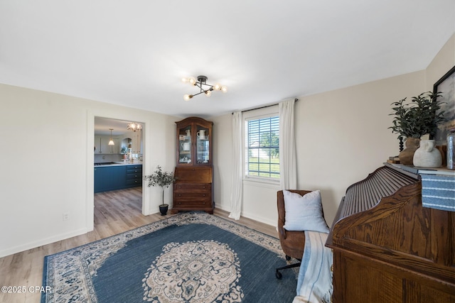 sitting room with an inviting chandelier, baseboards, and light wood-type flooring