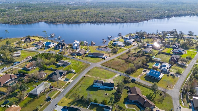 drone / aerial view featuring a residential view, a wooded view, and a water view