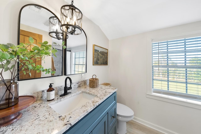 bathroom featuring toilet, wood finished floors, baseboards, vanity, and vaulted ceiling