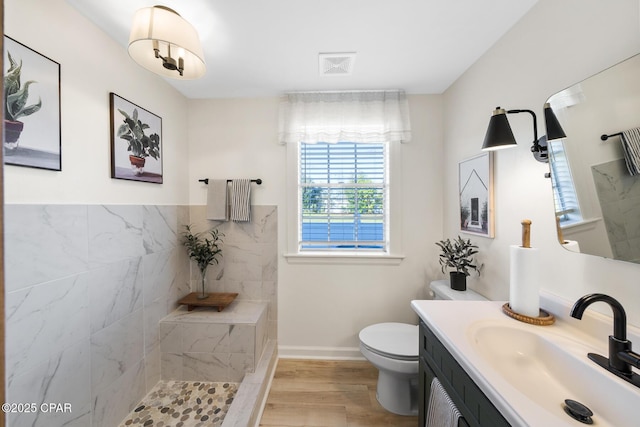 bathroom with vanity, wood finished floors, baseboards, walk in shower, and toilet