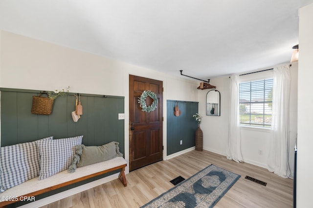 entryway with wood finished floors, visible vents, and wainscoting