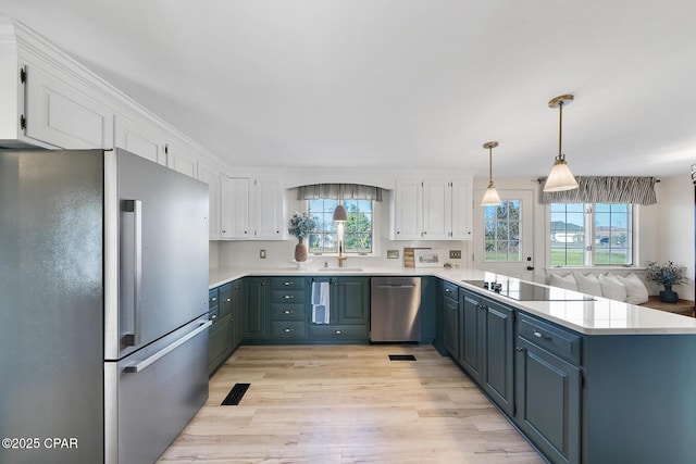 kitchen featuring a peninsula, light wood-style flooring, a sink, stainless steel appliances, and white cabinets