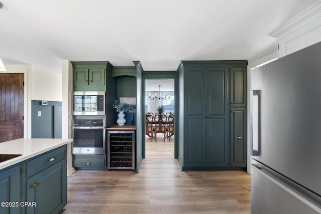 kitchen featuring light wood finished floors, beverage cooler, appliances with stainless steel finishes, and a chandelier