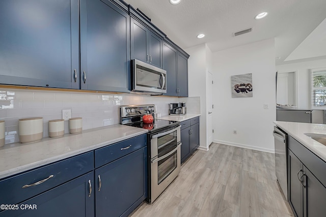 kitchen featuring visible vents, stainless steel appliances, decorative backsplash, blue cabinets, and light wood-type flooring