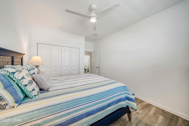 bedroom with visible vents, a ceiling fan, wood finished floors, a closet, and baseboards