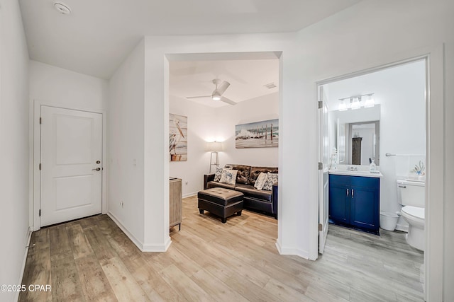 interior space with baseboards, light wood-style floors, visible vents, and ceiling fan