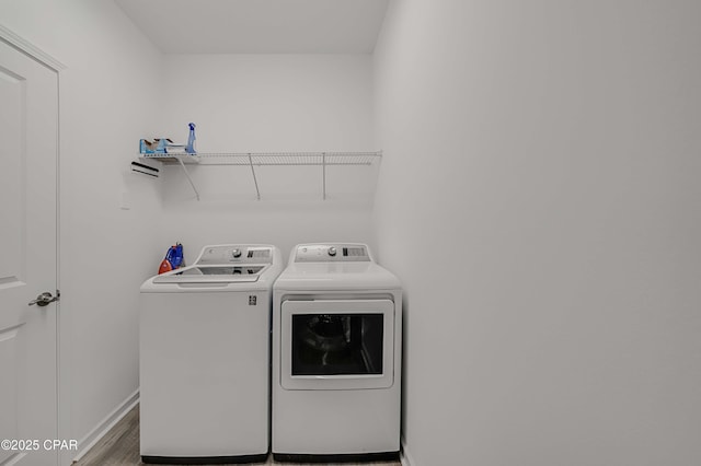 laundry room with laundry area, wood finished floors, separate washer and dryer, and baseboards