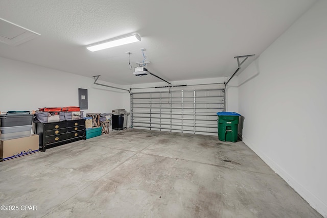 garage featuring electric panel, a garage door opener, and baseboards