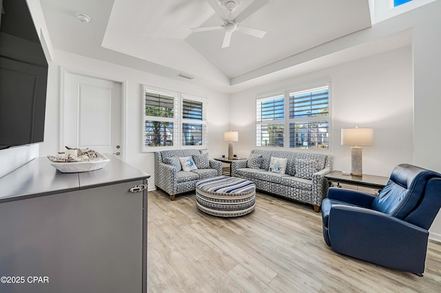 living area with a raised ceiling, light wood-style floors, ceiling fan, and vaulted ceiling