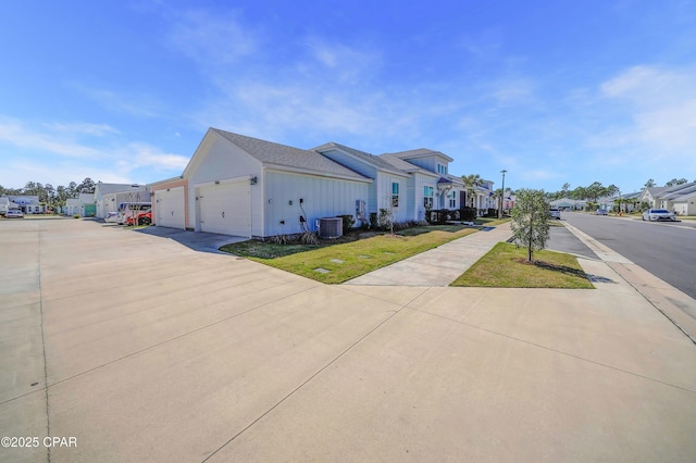 view of home's exterior with a residential view, central AC unit, concrete driveway, and a garage